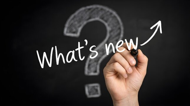 Human hand writing what is new on a dark chalkboard with a large white question mark