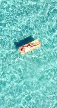 Woman floating on lilo inflatable mattress over blue transparent water surface in summer holiday vacation leisure activity. Female tourist have relax on the ocean. People and beach happy lifestyle