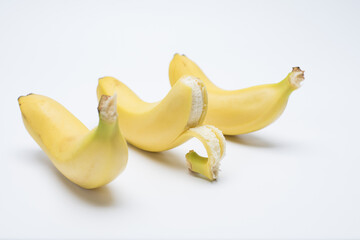 Ripe bananas with one peeled on white background © HoangVan