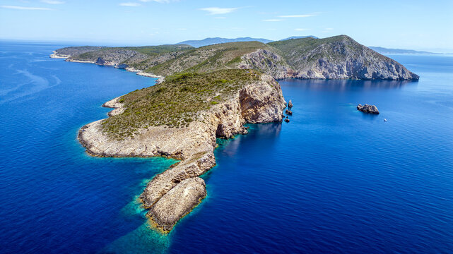 Aerial view of the rocky coastline and cliffs of Bisevo island surrounded by the deep blue Adriatic Sea in Bisevo, Split-Dalmatia County, Croatia.