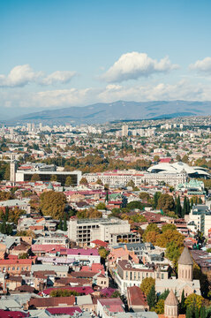 Tbilisi cityscape overlooks mountains beneath clouds