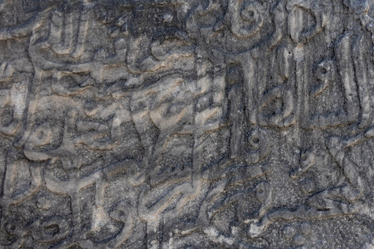Ancient carved Arabic script on stone. An ancient artifact. Ancient Arabic script on the surface of the stone. The Arabic alphabet. Arabic text background on a stone surface.
