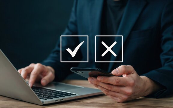 Businessman using laptop and smartphone with check and cross icons