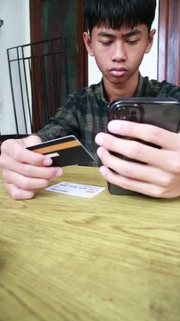 Young man using a credit card on his phone for digital transaction, digital business concept