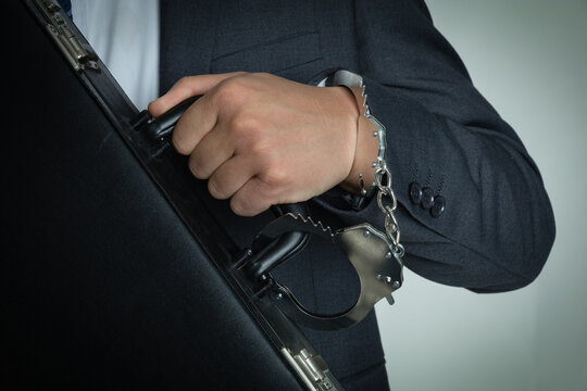 Handcuffed Businessman Holding Briefcase in White Collar Crime Concept