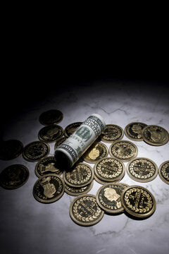 Rolled dollar bill and coins on marble surface representing savings and finance