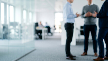 Fototapeta premium Three professionals engage in conversation in a modern office setting. The area is well-lit and features contemporary furnishings, emphasizing teamwork and collaboration.