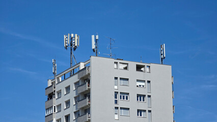 Cellular network base stations and panel antennas installed on the roof of a multi story concrete apartment building © hecos