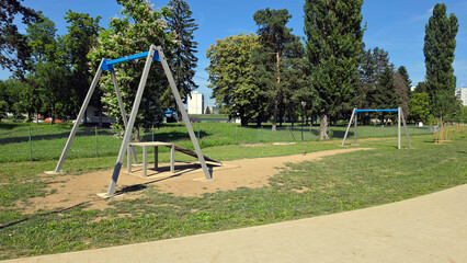 Obraz premium Outdoor public playground zip line track structure installed on a grass lawn next to a paved walkway