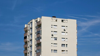 Fototapeta premium Upper stories of a beige multi story high rise apartment building under a clear blue sky