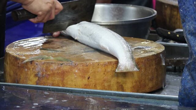 Slicing Raw Barracuda Fish on a Wooden Cutting Board with Cleaver 