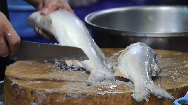 Close-up of Hands Preparing Whole Indian Salmon Fish (Rawas) with a Meat Cleaver