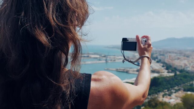 Woman capturing Malaga's scenic harbor and cityscape with her camera, embodying mindful exploration and travel inspiration.
