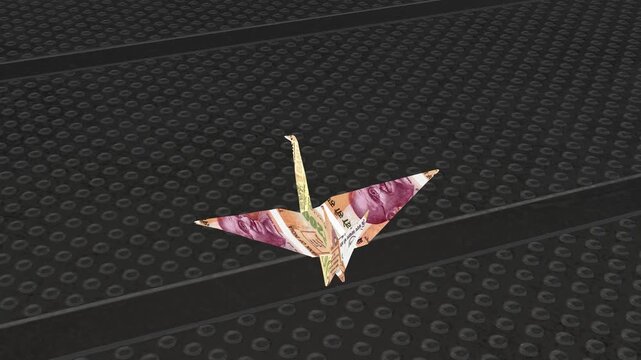 Loopable cinematic view of an origami crane bird meticulously folded from an Indian 200 Rupee note, sitting on a dark metal grid.