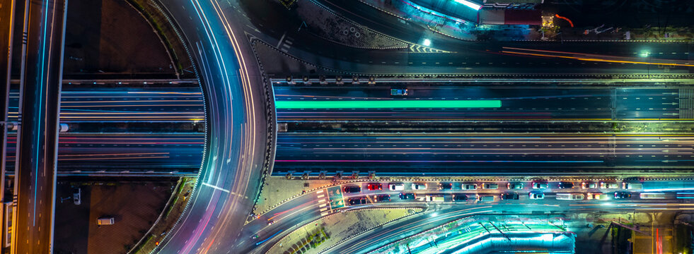 Aerial view of modern highway interchange with dynamic light trails at night, symbolizing smart city infrastructure, sustainable transportation, EV mobility, ESG investment, and future business growth