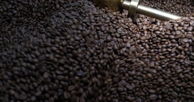 Roasting process in coffee roasting machine,Natural roast coffee beans mixing,mixing machine mixes roasted coffee beans in roaster, close up