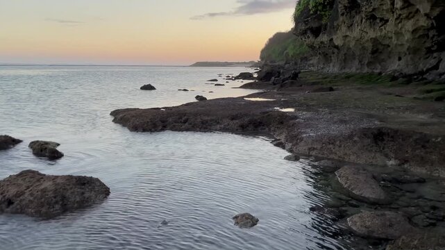 Horizontal Tilt Up Reveal of Rocky Coast and Cliff at Sunset in Bali
