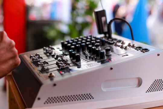 close-up, angled shot of a white professional audio mixing console board with numerous knobs, faders, and buttons