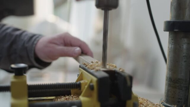 Craftsman drills wood in workshop vise during carpentry and woodworking process