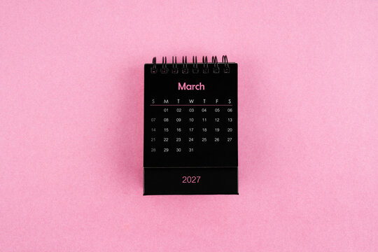 Black calendar for March 2027 year on pink color background.