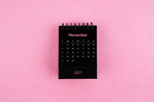 Black calendar for November 2027 year on pink color background.