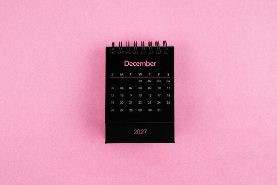 Black calendar for December 2027 year on pink color background.