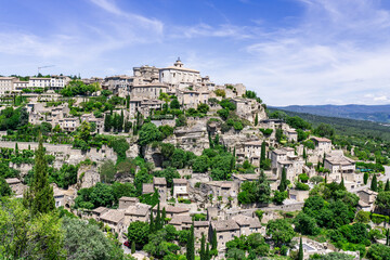 Naklejka premium Gordes clinging to cliffs above rural Provence, Tourist village at top of hill