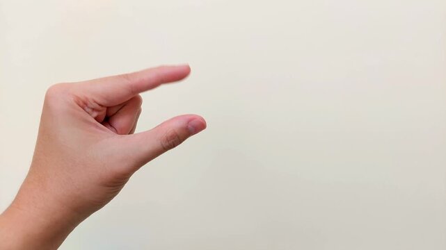 Hand motion with thumb and index finger repeatedly moving together against neutral background with copy space, for pinching gesture, measuring small sizes, body movement, and motor skills concepts.