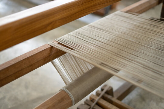 Macro shot of a traditional wooden loom with stretched threads. Authentic handmade textile weaving process in Indonesia.