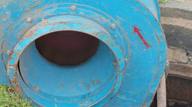 Close-up of blue industrial centrifugal fan with red directional arrow in operation outdoors.