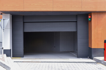 Fototapeta premium Partially open automatic sectional garage door on modern building facade