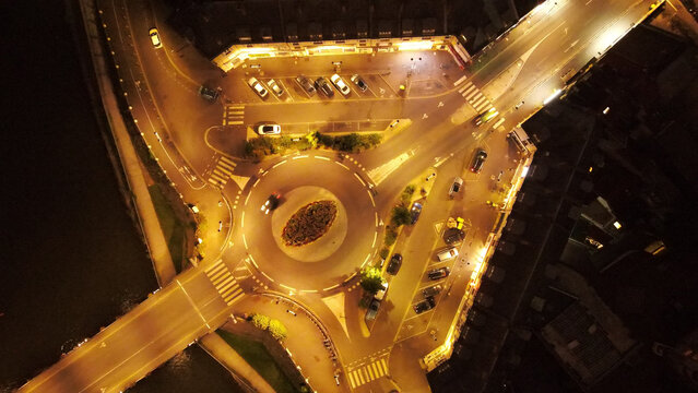 Aerial view of a roundabout illuminated at night with surrounding streets, parked cars, and urban infrastructure in Pontoise, Ile-de-France, France.