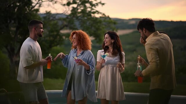 Friends dancing, laughing, sipping colorful drinks at an evening gathering in a beautiful countryside villa