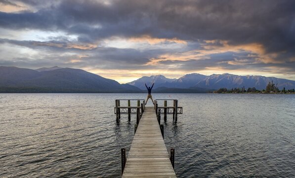 Juger man takes a skydive, jetty at the lake, Lake Te Anau at sunset, Te Anau, South Island, New Zealand