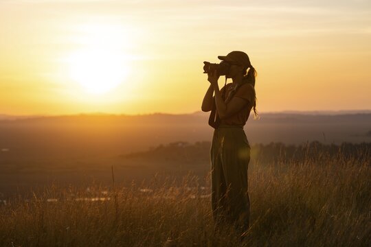 Young woman taking pictures at sunset, standing in tall grass, landscape, view of Lake Victoria and Mabamba swamp, Lake Victoria, Uganda