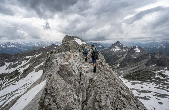 Hiker and hiker on a ridge trail with remnants of snow, mountain panorama with peak High light, dramatic cloudy sky, Heilbronner Weg, Allg&auml;u Alps, Allg&auml;u, Bavaria, Germany