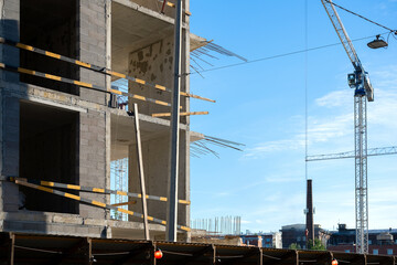 Naklejka premium Building Under Construction with Tower Crane Against Blue Sky