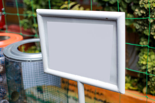close-up shot of a blank white rectangular signboard with a clean white frame, attached to a metal post