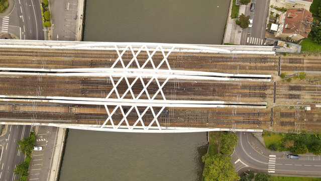 Aerial view of a white steel railway bridge crossing the Oise river with trains on the tracks in Pontoise, Ile-de-France, France.