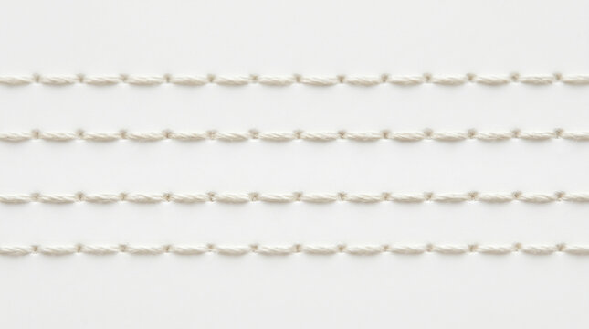 Close-up view of four parallel rows of white stitching on a white background, creating a textured pattern.