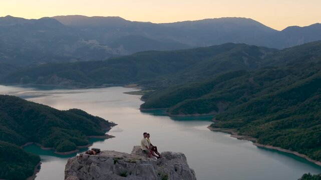 Albania boasts breathtaking views of Bovilla Lake. A couple witnesses the serene landscape as the sun sets over the water, casting golden hues on the surrounding mountains.