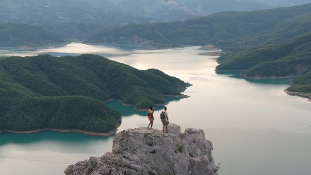 Albania welcomes you to Bovilla Lake, where a couple of adventure seekers explore rocky cliffs. Nature lovers admire turquoise waters and lush landscapes, perfect for unforgettable memories 