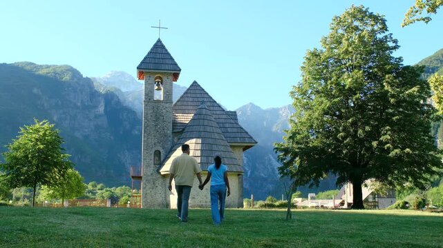 Albania Theth offers captivating views as visitors stroll toward a beautiful church nestled in the mountains. This perfect holiday destination is ideal for peaceful exploration