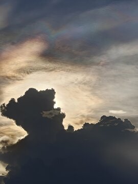 Iridescent Cloud Streaks Above Dark Cloud Silhouette at Dusk