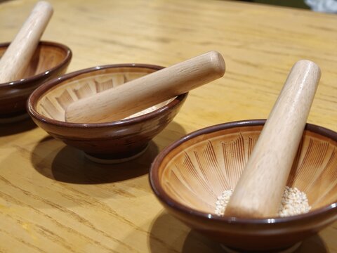 Wooden Mortar and Pestle Bowls with Sesame Seeds on Table