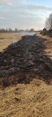 Obraz premium Scorched Earth Field Aftermath showing a long black trail left by a grass fire. Use for ecological damage studies, agricultural recovery blogs, and climate change graphics.