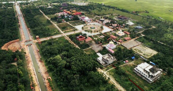 Aerial drone view of the Lumbini monastic zone showing a long canal, gardens, temples and tree-lined pathways stretching across the landscape in Nepal.