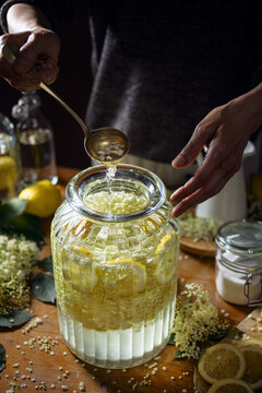 Close up of preparation of elderberry flower syrup,  soft light with deep shadows.
