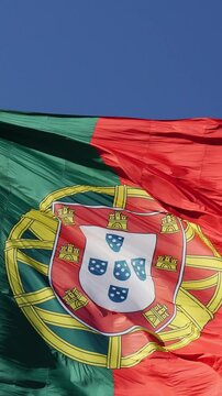 The detailed armillary sphere and official coat of arms filling the frame on a big fluttering flag of Portugal near Edward VII Park in Lisbon. Macro shot. Vertical Video