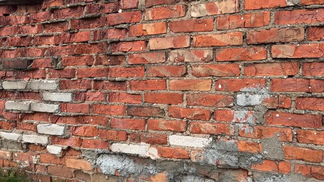 Texture of old brick wall with cracked mortar and concrete patches, weathered urban building background